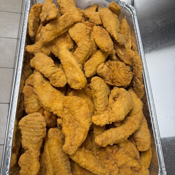 A large aluminum tray filled with golden-brown, crispy fried chicken tenders.