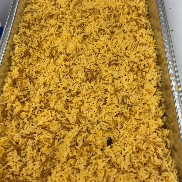 A large aluminum tray filled with yellow rice and vermicelli noodles, ready for serving.